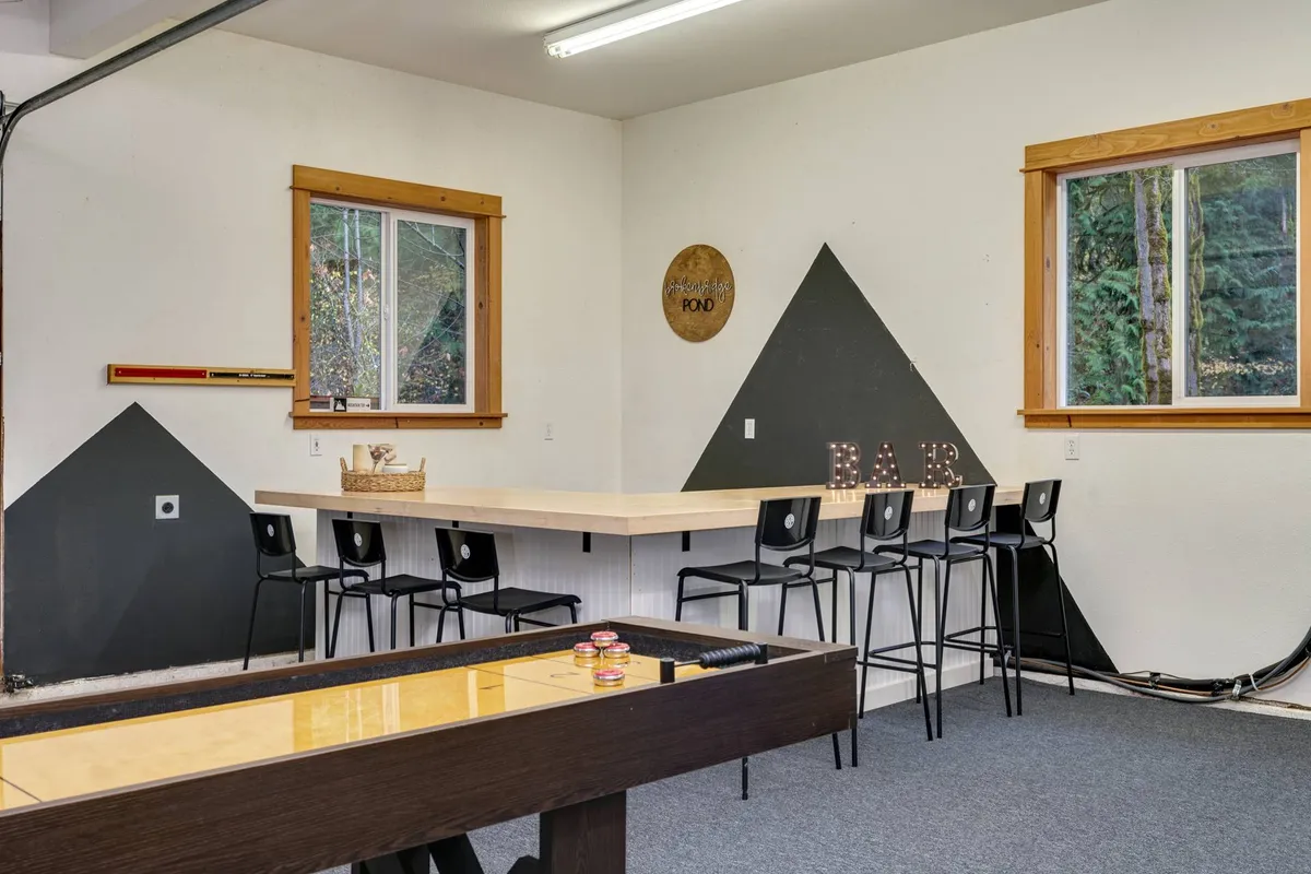 An interior view centered on a large dining table flanked by bar stools and a game table, set within an open area designed for both dining and recreation. Decorative elements and ample space foster a lively, sociable mood.
