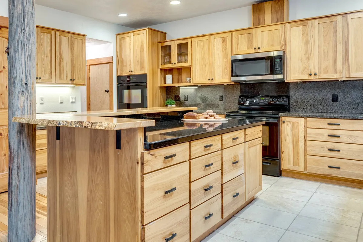 A close-up of the kitchen area, highlighting a generous kitchen island with a black granite countertop, rich wooden cabinetry, and sleek stainless steel appliances. The layout is functional and welcoming, ideal for meal prep and casual conversation.