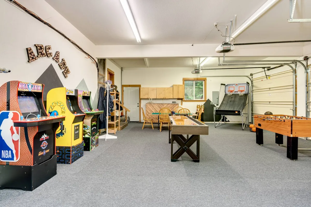 A lively game room equipped with multiple arcade machines, a foosball table, a pool table, and a comfortable seating area. Groups of friends or family can be imagined gathering here for friendly competition and laughter.